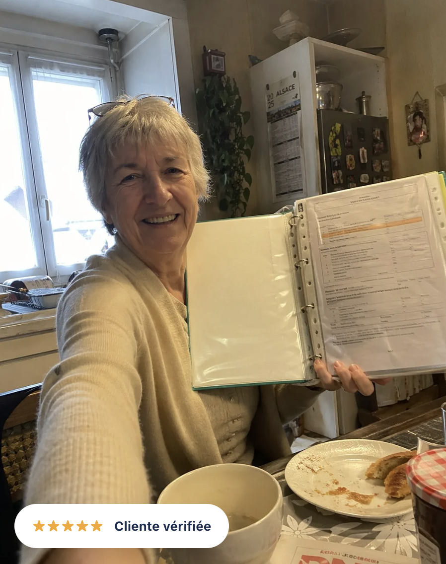 Une cliente du Kit Protection Familiale EHPAD souriante, son classeur ouvert à la main, dans sa cuisine